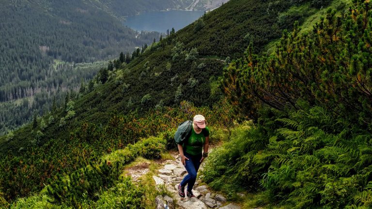 Ieva climbing a mountain path on one of her first hikes, with a small lake visible in the distance