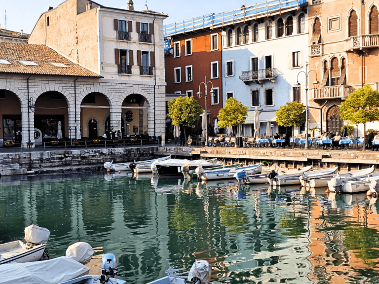 Desenzano’s old harbour with colourful houses and a few small boats tied in the narrow docking area.