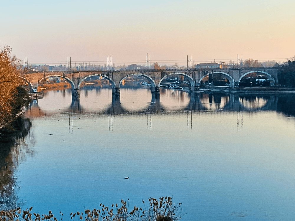 Where to stay on Lake Garda without a car: Peschiera or Desenzano? 1 Railway bridge Ponte ferroviario di Peschiera del Garda crossing over the river on a clear day.