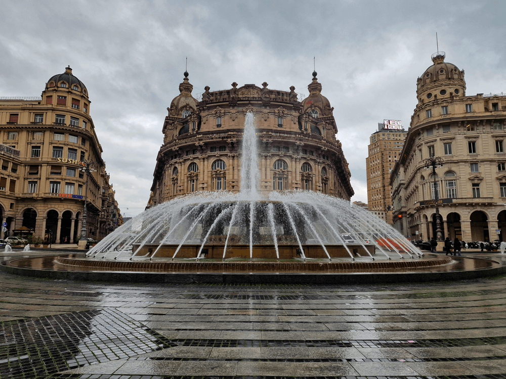 4 days in Liguria: an easy coastal trip 1 The main fountain at Piazza De Ferrari in Genoa with water spraying outward and elegant historic buildings in the background.