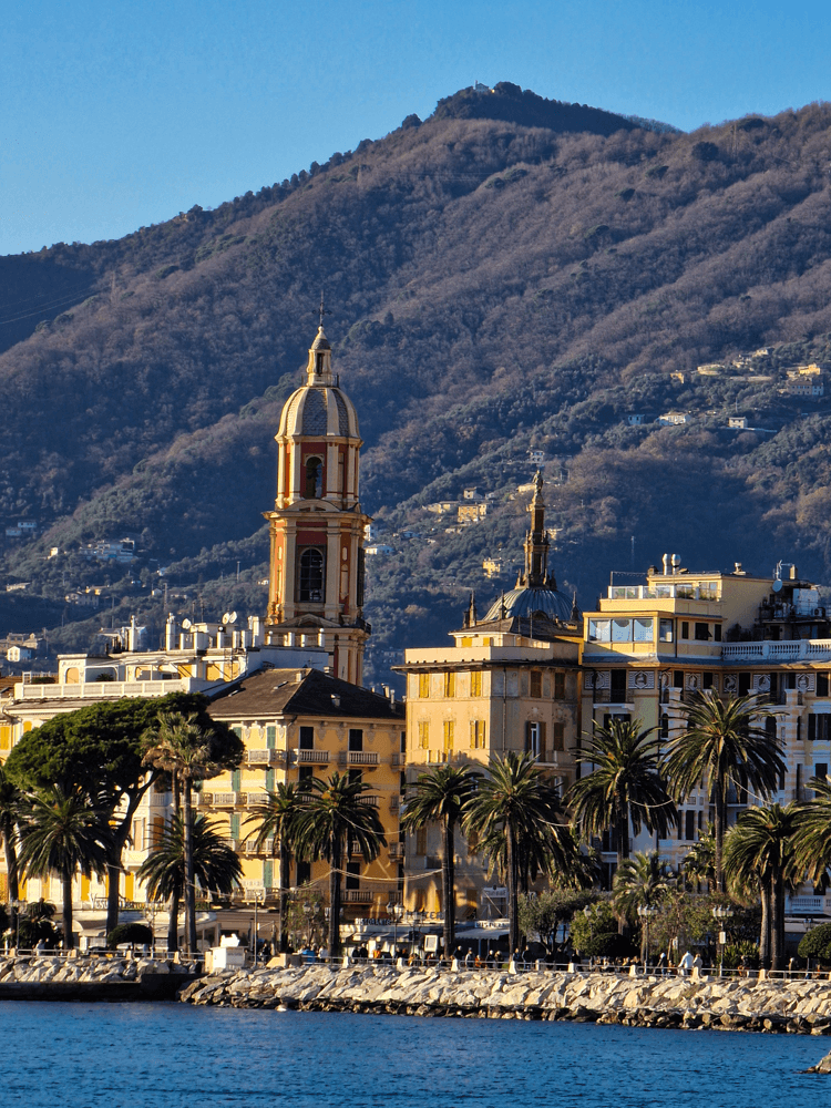 View of Rapallo’s colourful buildings and a church tower, photographed from the shore at an angle that looks as if the scene was taken from the water.