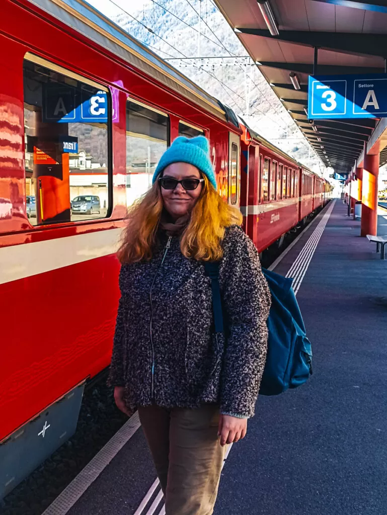 Bernina Express: a simple day trip into the Swiss Alps 2 A woman standing next to the red Bernina Express at Tirano railway station.