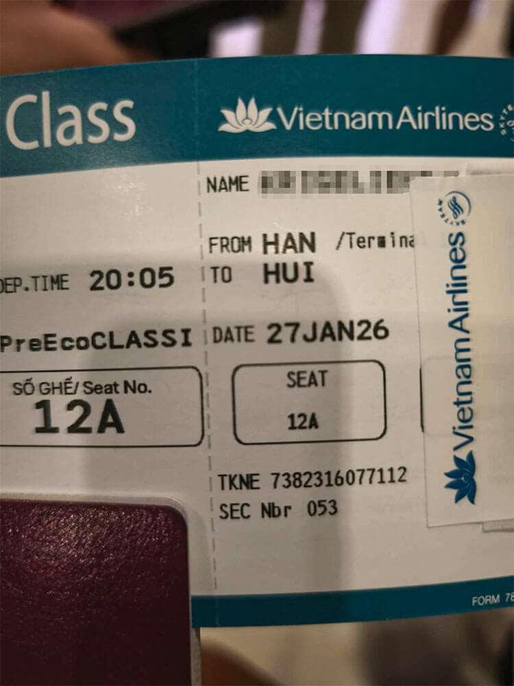 First time flying: what to do at the airport 1 A close up photo shows a Vietnam Airlines boarding pass with seat 12A. The route reads from HAN to HUI with the date 27JAN26 visible.