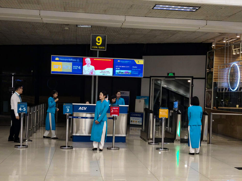 First time flying: what to do at the airport 7 A boarding gate area shows a large sign for gate 9 above a Vietnam Airlines counter. Airline staff in turquoise uniforms stand near queue markers and the boarding entrance.