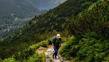 Ieva climbing a mountain path on one of her first hikes, with a small lake visible in the distance