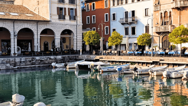 Desenzano’s old harbour with colourful houses and a few small boats tied in the narrow docking area.